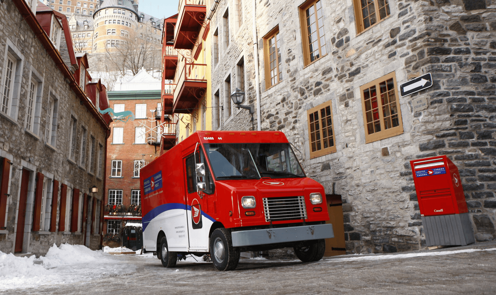 Une camionnette de Postes Canada est stationnée à côté d’une boîte aux lettres publique.